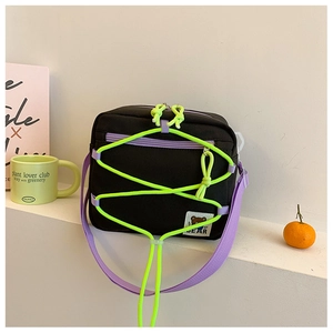 Detail of black canvas boy bag with neon green cords and purple woven shoulder strap