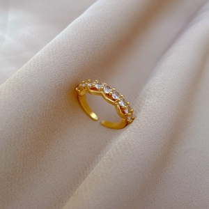 Close-up of gold-plated adjustable ring with zircon pavé setting on champagne silk