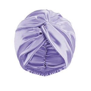 Dettaglio del turbante in raso viola con nodo incrociato frontale e trama setosa