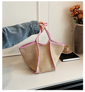 Detail of hand-woven straw tote bag with pink fabric trim and contrast stitching