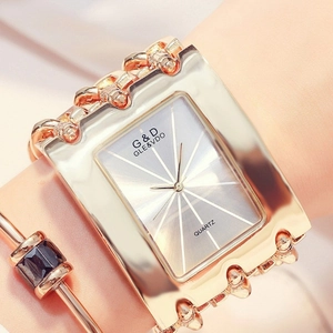 Close-up of gold square quartz watch with metal chain strap on woman's wrist