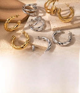 Macro shot of titanium steel C-shaped twisted earrings in gold and silver finishes