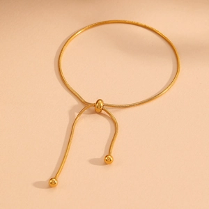 Detail of adjustable gold snake chain bracelet with tassel slider and metallic beads