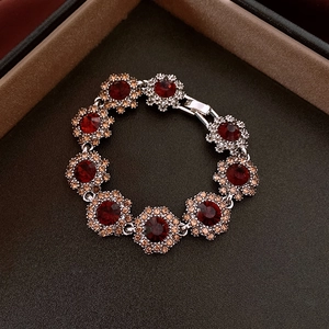 Detailed macro view of a floral silver bracelet with red crystals in a black gift box