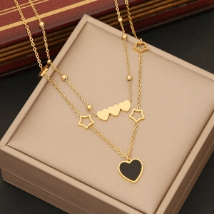 Double-layered gold necklace with black heart pendant and star charms on jewelry box