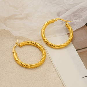 French style gold twisted hoop earrings in stainless steel on artistic paper background