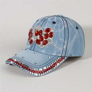 Detail of light blue denim baseball cap featuring red rhinestone heart and studded brim