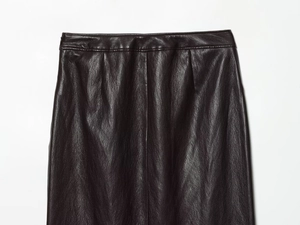 Détail d'une jupe en similicuir marron foncé à taille haute avec coutures et plis fins