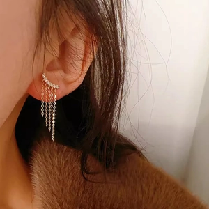 Close-up of golden multi-layered tassel earrings with sparkling zircon on model