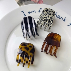 Chic acetate hair claws in leopard and polka dot patterns on a ceramic display