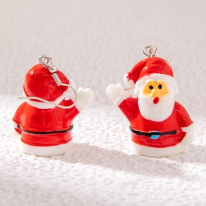Close-up of handmade Santa Claus earrings with red and white enamel on soft fabric