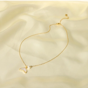 Detailed close-up of a golden mermaid tail pendant with natural pearl and white shell inlay