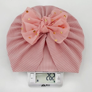 Pink ribbed baby hat with large tulle bow weighing 26.2g on a digital scale