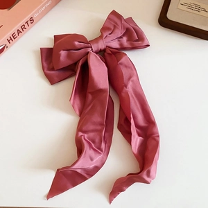 Detail of a pink silk bow hair claw clip with pearls on a white desktop setting