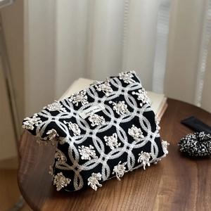 Détail de la broderie florale blanche et de l'étiquette sur le petit sac en toile noire