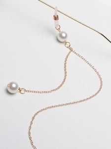 Close-up of golden metal eyeglass chain with white pearls and anti-slip rubber loops