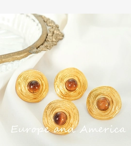 Macro shot of gold vintage stud earrings with amber tiger eye stones on white silk