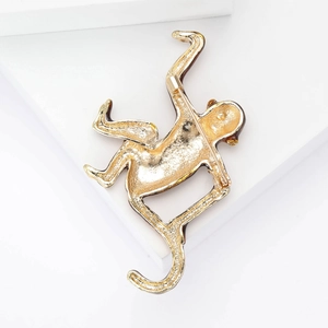 Golden monkey animal brooch pin with sparkling rhinestones on a white minimalist background