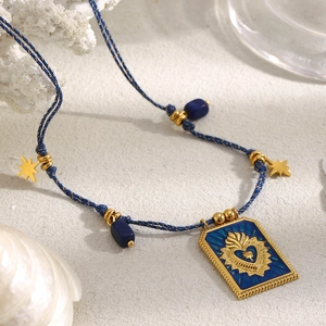 Detail of 18K gold-plated sacred heart square pendant with blue enamel and woven cord