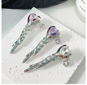 Detailed view of three metallic liquid bow hair clips with pink and purple heart gems