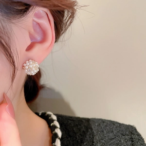 Detailed close-up of clusters of faux pearls and zircons on elegant floral stud earrings