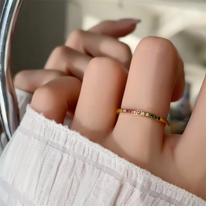 Minimalist 18k gold plated rainbow zircon eternity ring on hand with elegant sleeve background