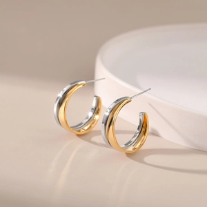 Detailed macro view of two-tone gold and silver layered C-shape metallic stud earrings