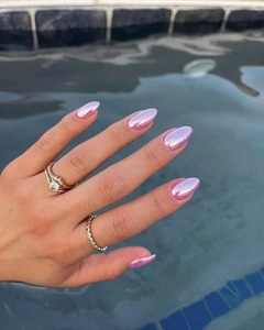 Gros plan d'ongles chromés roses en amande portés au bord d'une piscine ensoleillée