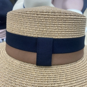 Macro shot of fine woven texture and bicolor ribbon detail on a flat top straw hat