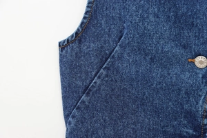 Dettaglio della tasca in denim blu scuro con cuciture arancioni e bottone metallico per jeans