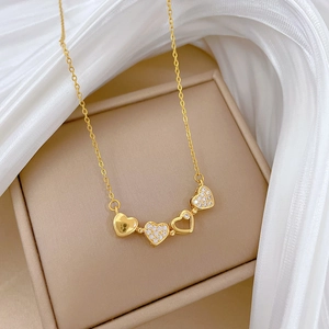 Detailed close-up of a gold heart-shaped clover necklace with cubic zirconia on silk