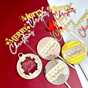 Flat lay of diverse Merry Christmas acrylic and wooden cake toppers in gold and red colors