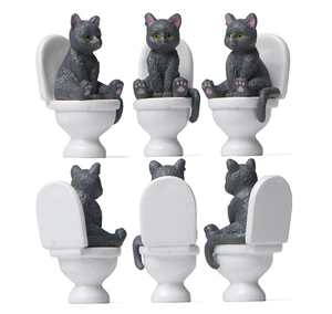 Front and back views of gray cat figurines sitting on white miniature toilets