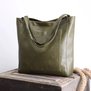 Détails de texture du grand cabas vintage en cuir ciré vert sur coffre en bois