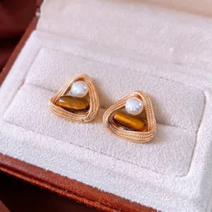 Vintage gold tiger eye stone and pearl stud earrings displayed on a velvet jewelry box