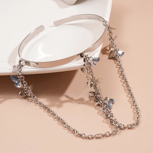 Detail of silver butterfly tassel upper arm cuff with dangling charms on a ceramic tray
