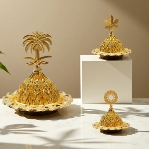 Detailed view of three gold hollow metal incense burners with palm and maple lid finials