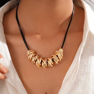 Close-up of golden geometric nested rings on black cord necklace worn by a model