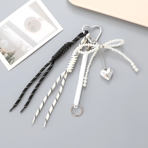 Porte-clés avec nœud, pendentif cœur et cordes tressées sur un bureau gris épuré