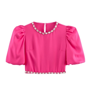 Detail eines rosenroten Satin-Crop-Tops mit Puffärmeln und Strass am Halsausschnitt