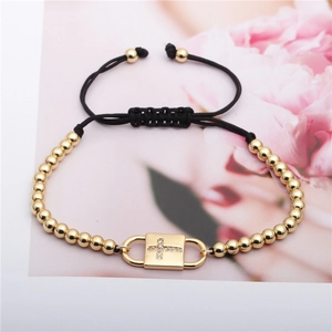 Adjustable black rope bracelet with gold beads and a zircon cross pendant on card