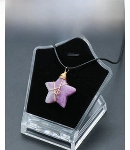 Detail of amethyst star pendant with wire-wrapped gold finish on a black necklace
