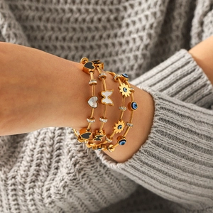 Four-piece gold stackable bangle set with evil eye, butterfly, shell heart and sunflower charms
