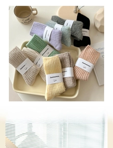 Dettaglio di calze di lana in colori della terra in un vassoio con confezione minimalista