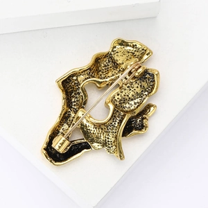 Detailed back view of golden metal brooch with secure safety pin closure on white stand