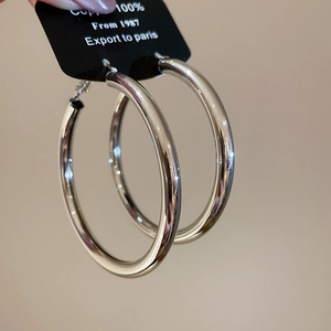 Detailed view of polished silver hoop earrings with copper material label on card