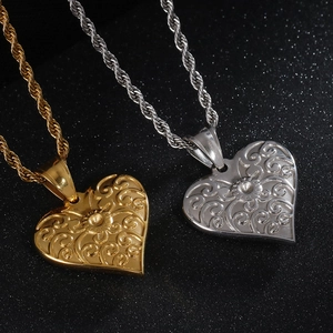 Detail of gold and silver heart pendants with swirl engraving on twisted rope chain