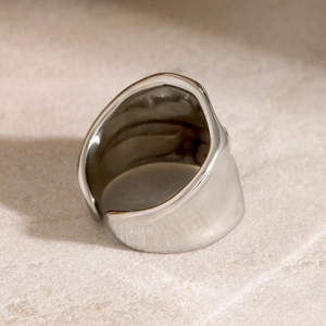 Polished wide hammered texture ring in silver finish on marble surface close-up