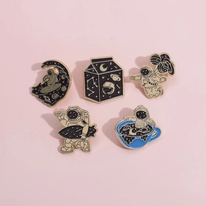Flat lay of five creative enamel space badges featuring astronauts on pink background