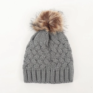 Detailed close-up of dark grey cable knit baby hat with a fluffy faux fur pom-pom